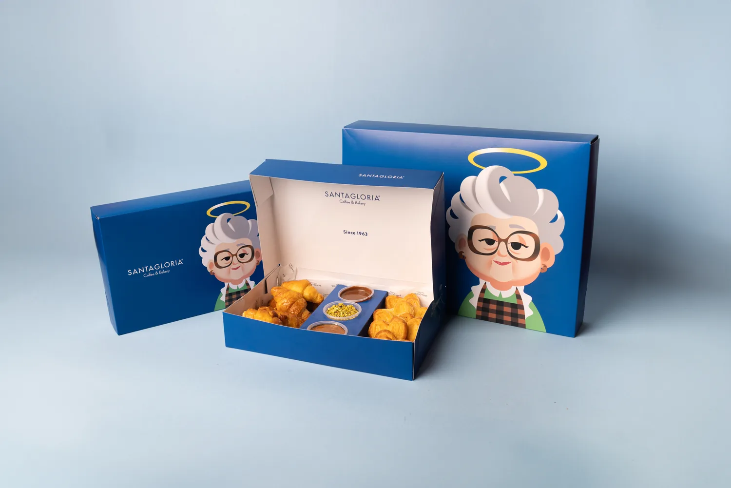 Caja azul SANTAGLORIA abierta con Glorias dulces sobre un fondo claro